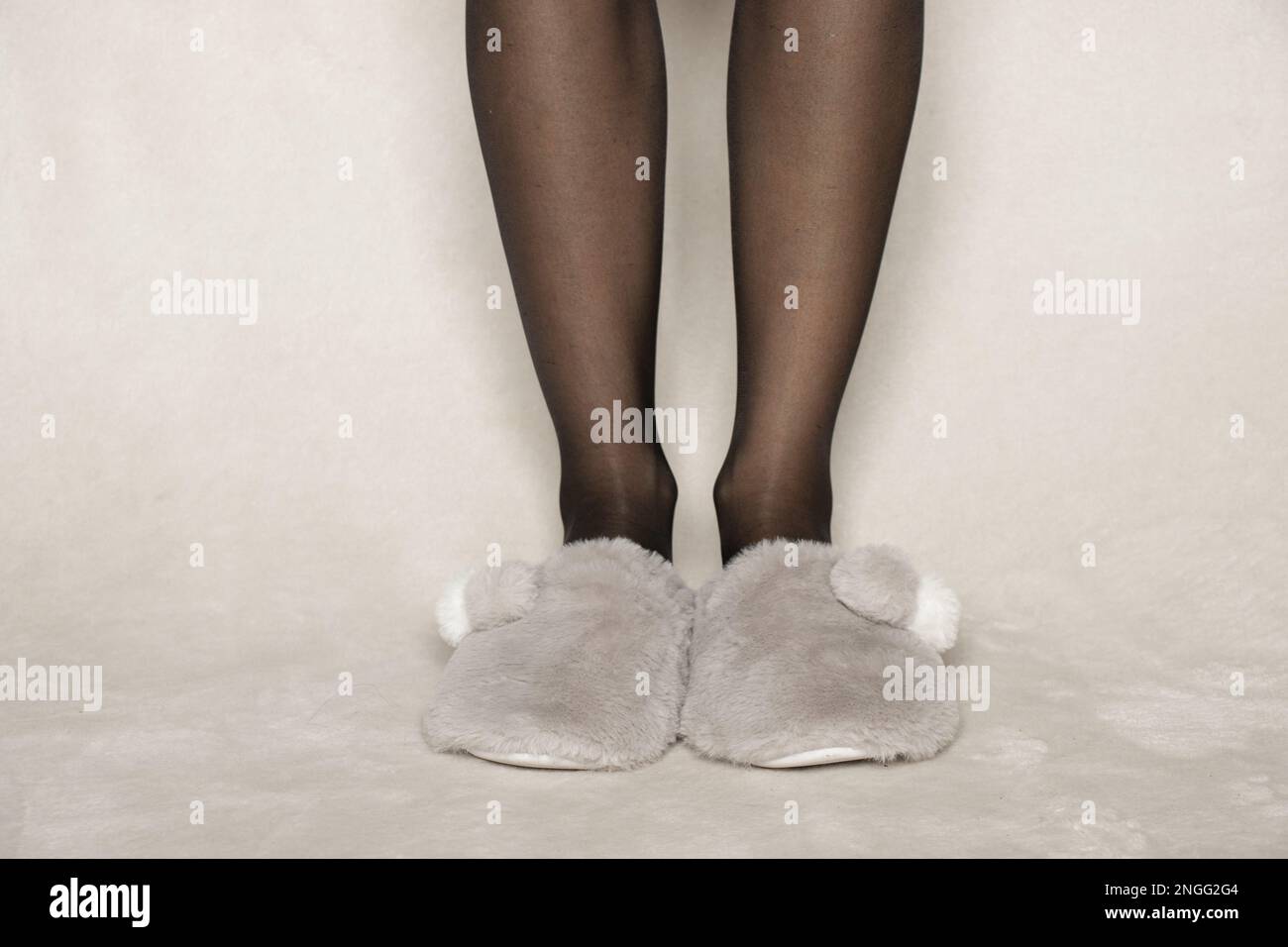 female-legs-in-black-nylon-tights-in-gray-slippers-on-the-floor-at-home-in-winter-2NGG2G4.jpg